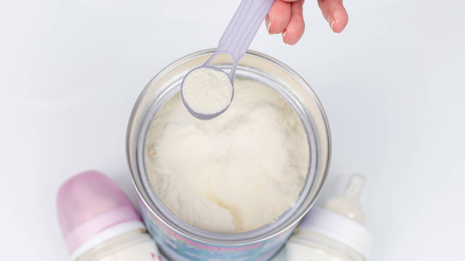 Foto detalle de la leche en polvo que una madre esta midiendo con la cucharilla para preparar el biberón de su bebé ya que ha optado por la lactancia artificial