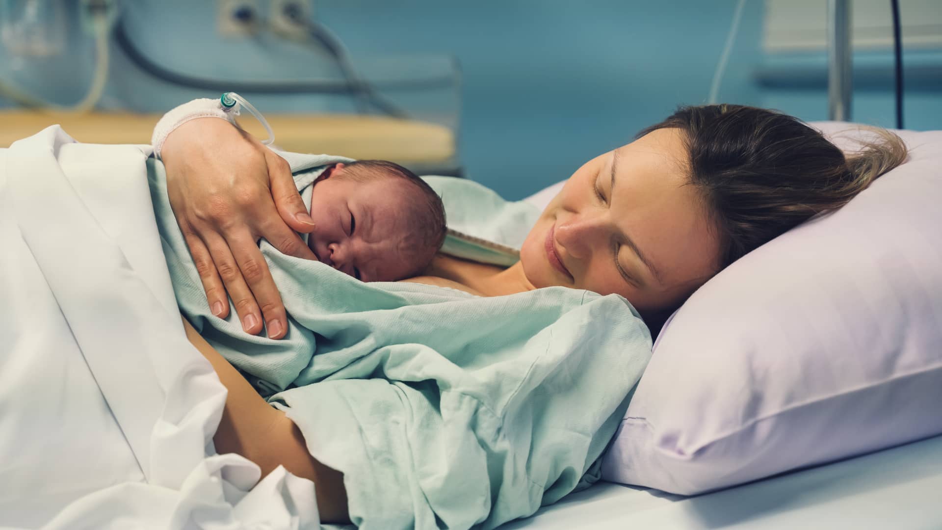 Madre aun en el hospital tras el parto con su bebe recién nacido en brazos