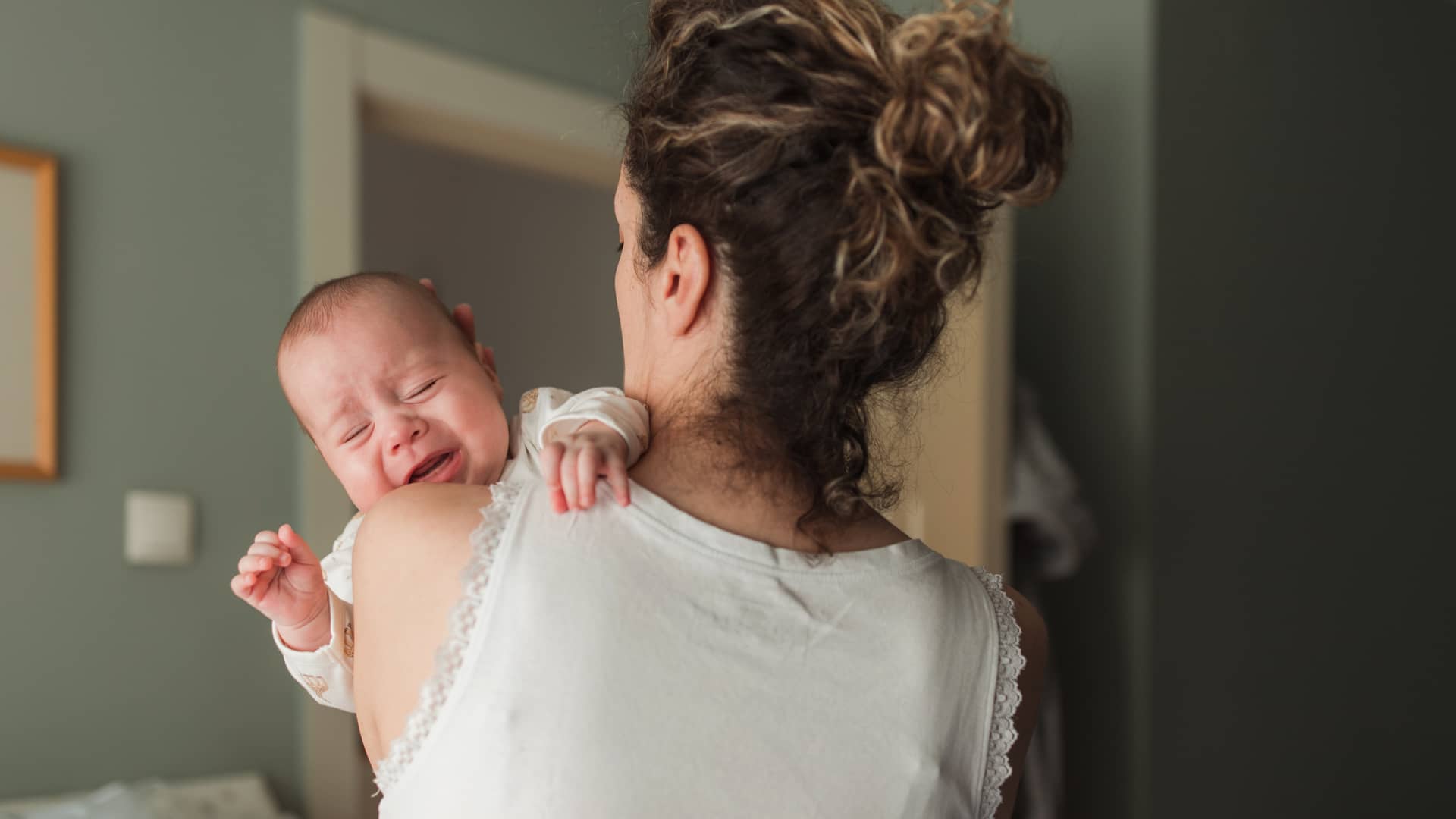 Bebé recién nacido llorando en brazos de su madre durante el postparto
