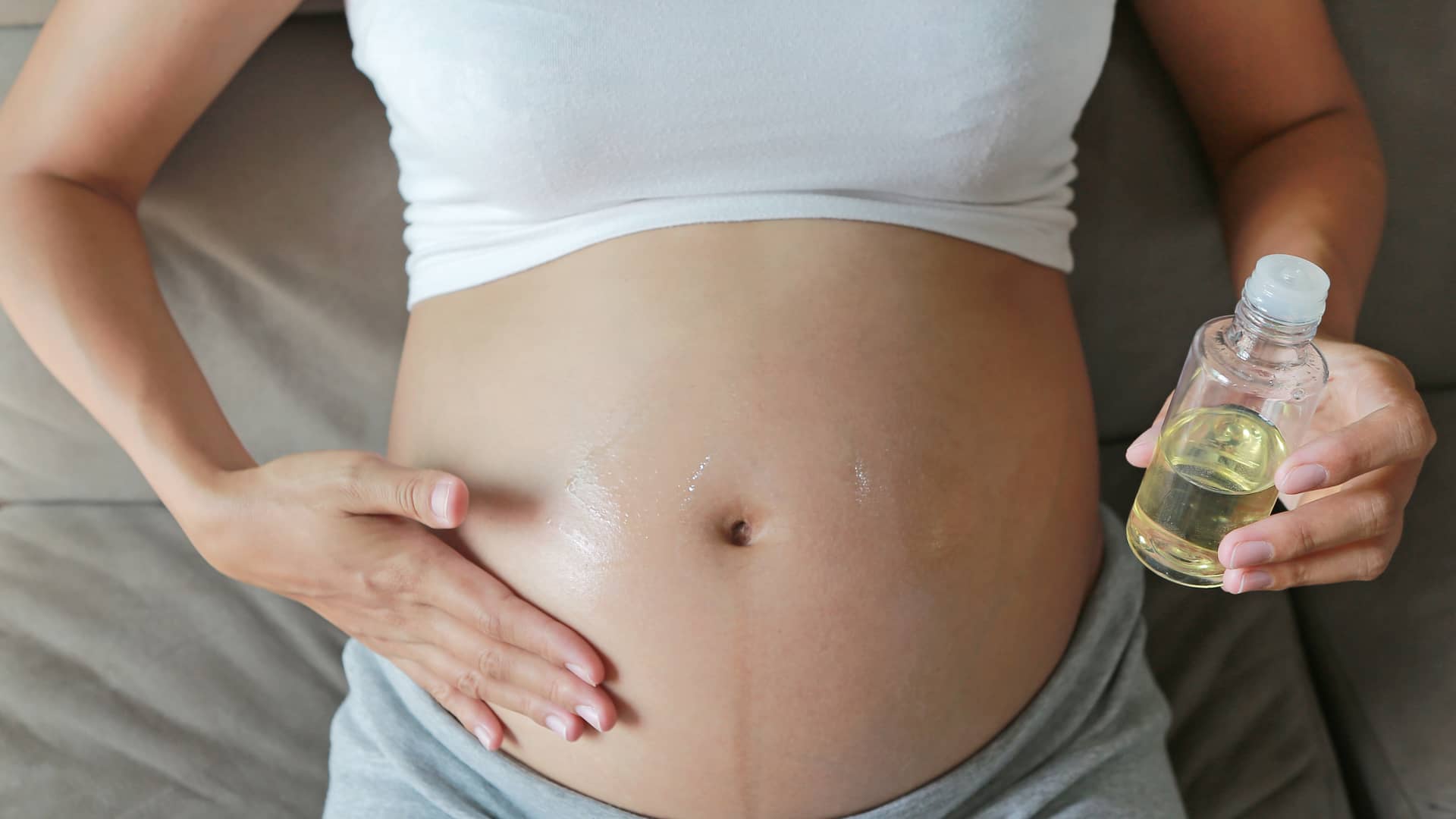 Barriga de una embarazada de 35 semanas hidratándose la piel para que no le salgan estrías