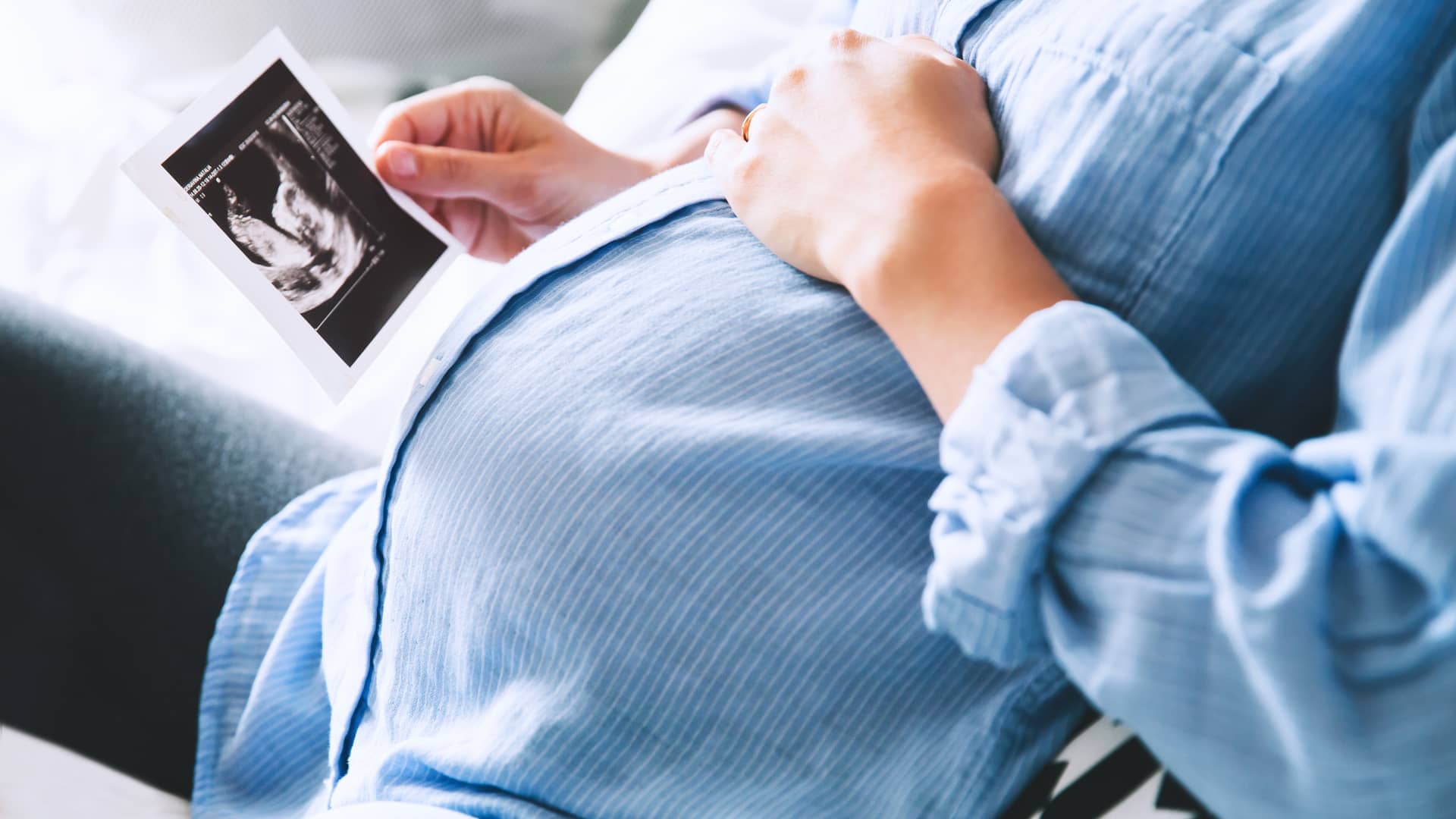 Mujer embarazada sostiene una ecografía de su bebé tras una revisión médica por el embarazo