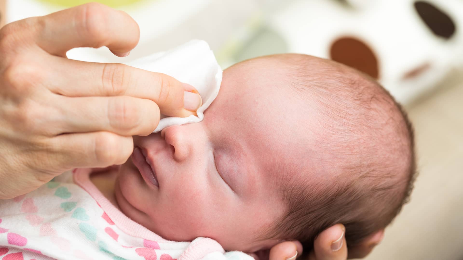 una mama limpiando los ojos de su bebe para evitar que tenga el lagrimal obstruido